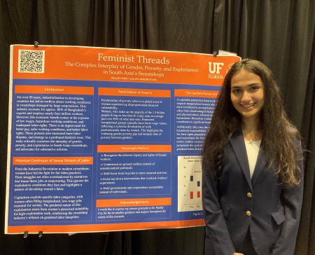 A woman is smiling while standing next to a presentation board.